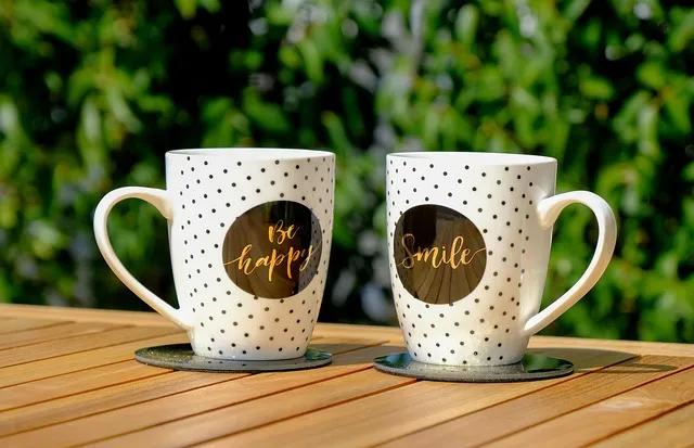 2 Mugs on a table, one with 'be happy' on and one with 'smile' on