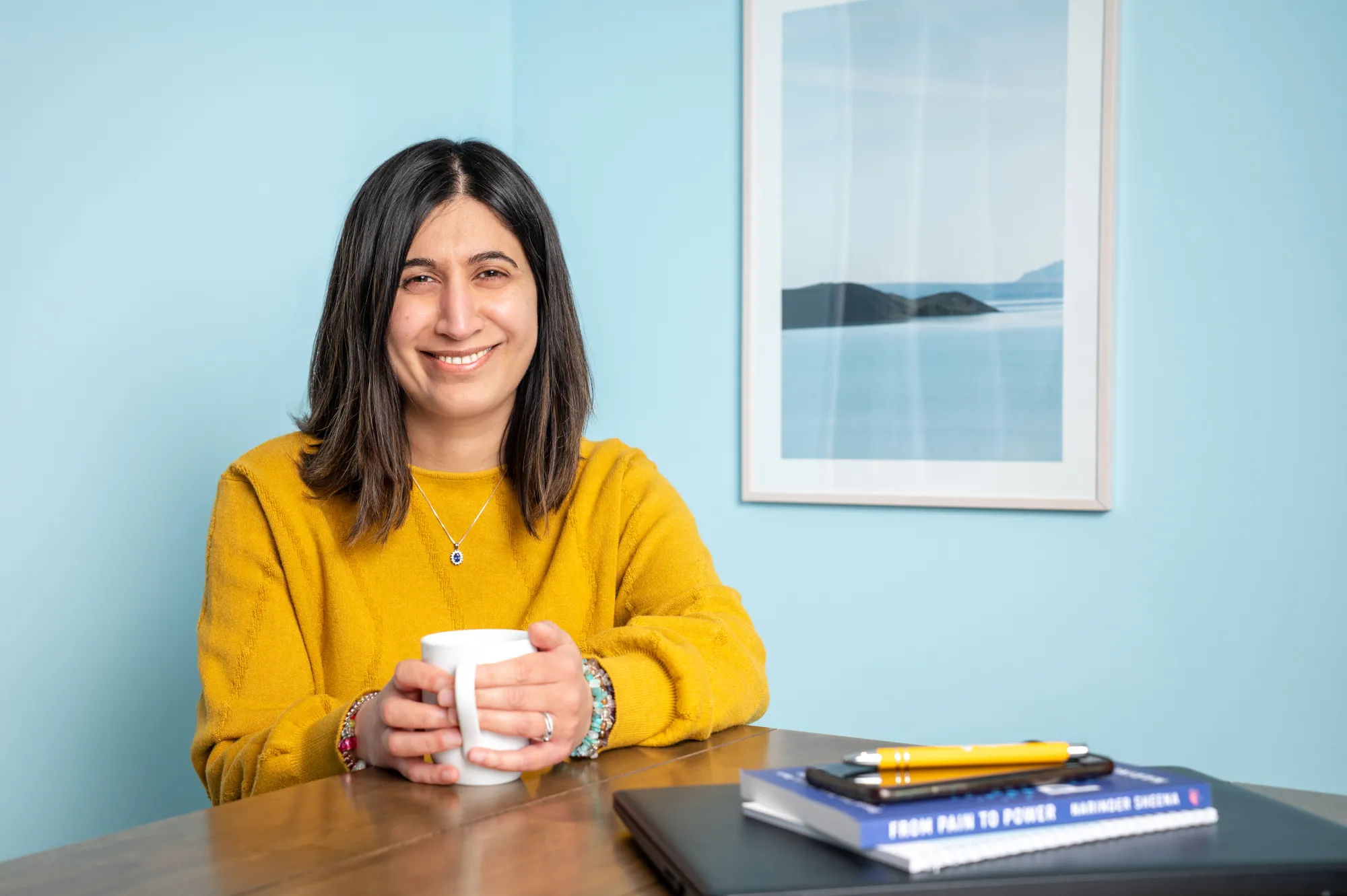 Narinder holding a mug on a table